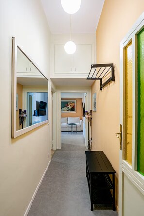 A hallway with a white door, a black bench, and a painting on the wall. - New Flat with Artistic Flair (Milano)