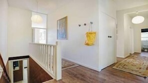 Ein Flur mit Holzboden, weißer Wand, einer Tür und einem hängenden gelben Gegenstand.