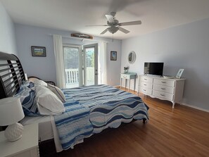Une chambre à coucher comprenant un lit, un bureau, un téléviseur et un ventilateur de plafond.