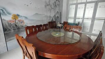 Ein runder Holzesstisch mit Stühlen, einer Glasplatte und einem Wandgemälde.