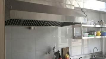 Una cocina con electrodomésticos de acero inoxidable, una campana extractora y un lavamanos.