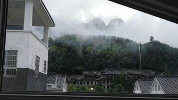 A view of a building with a traditional roof and a mountain in the background.