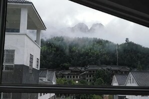A view of a building with a traditional roof and a mountain in the background.