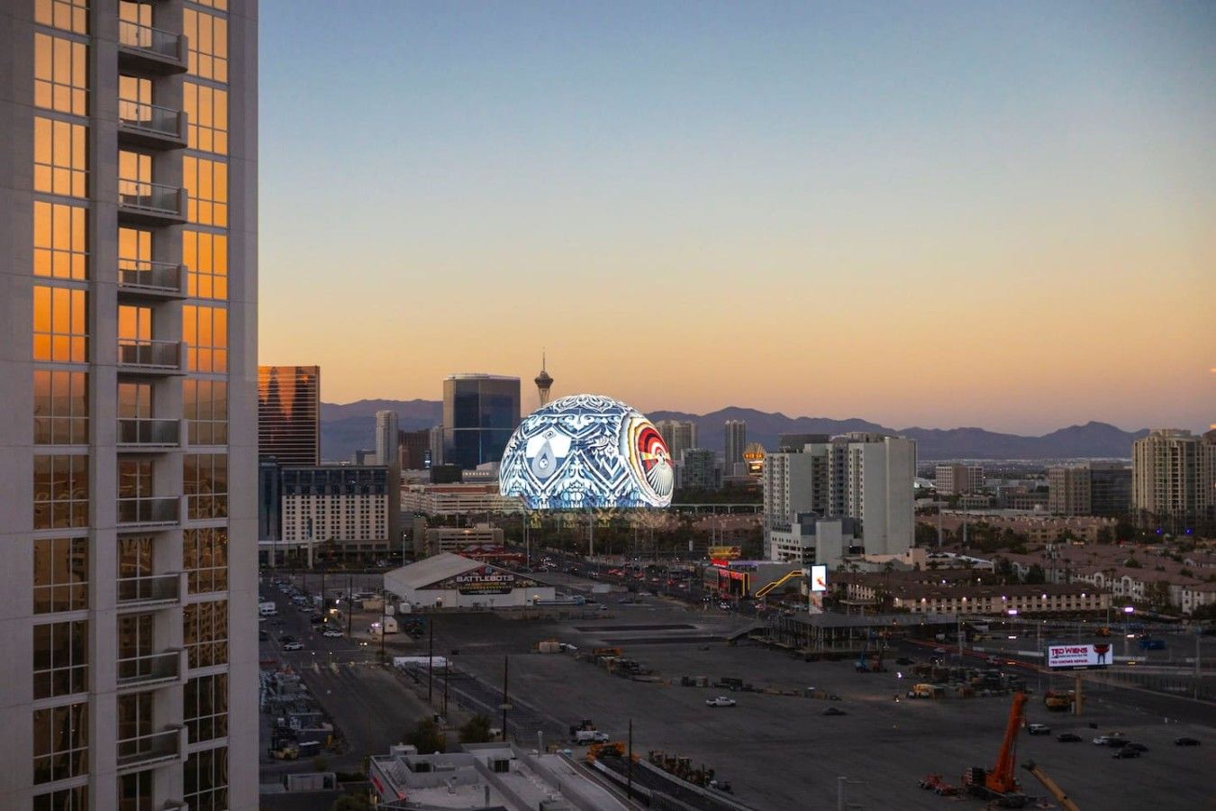 A cityscape with a prominent building featuring a large, illuminated spherical structure.