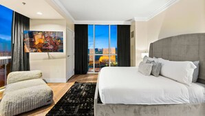 Hotellihuone, jossa on suuri sänky, näköala kaupunkiin, taulu seinällä ja ikkuna, jossa on verhot.
