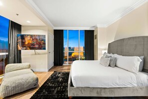 Une chambre d’hôtel avec un grand lit, une vue sur la ville, un tableau au mur et une fenêtre avec des rideaux.