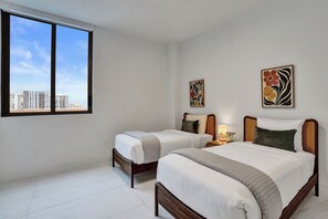 Ein Hotelzimmer mit zwei Betten, einem großen Fenster und Bildern an den Wänden.