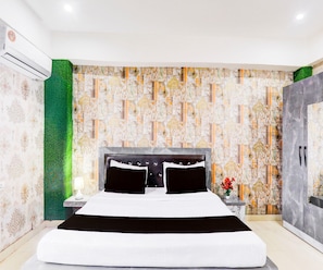 A modern bedroom with a large bed, a nightstand, a green textured wall, and a patterned wallpaper. - Classic Grand Jvi Resort & Marriage Lawn (Faizabad)