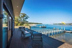 A deck with outdoor seating overlooking a body of water and dock. - SouthWind your premier escape destination in Merimbula (Merimbula)