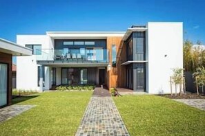 A modern two-story house with a paved driveway, a balcony, and a well-maintained lawn. - SouthWind your premier escape destination in Merimbula (Merimbula)