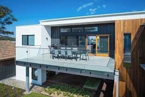 A modern house with a glass balcony, a dining area, and a wooden deck. - SouthWind your premier escape destination in Merimbula (Merimbula)