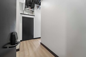 A hallway with a black door, a handrail, and a wall-mounted air conditioning unit. - Downtown Nights Await Petco Park & Gaslamp Fun!! (San Diego)