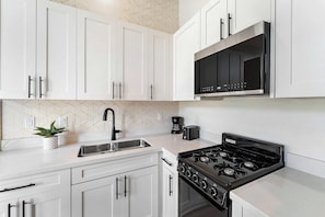 A kitchen with white cabinets, a black stove, a coffee maker, and a toaster. - Downtown Nights Await Petco Park & Gaslamp Fun!! (San Diego)