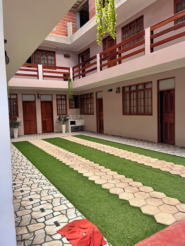 A courtyard with a central lawn, stone pathway, and wooden doors.