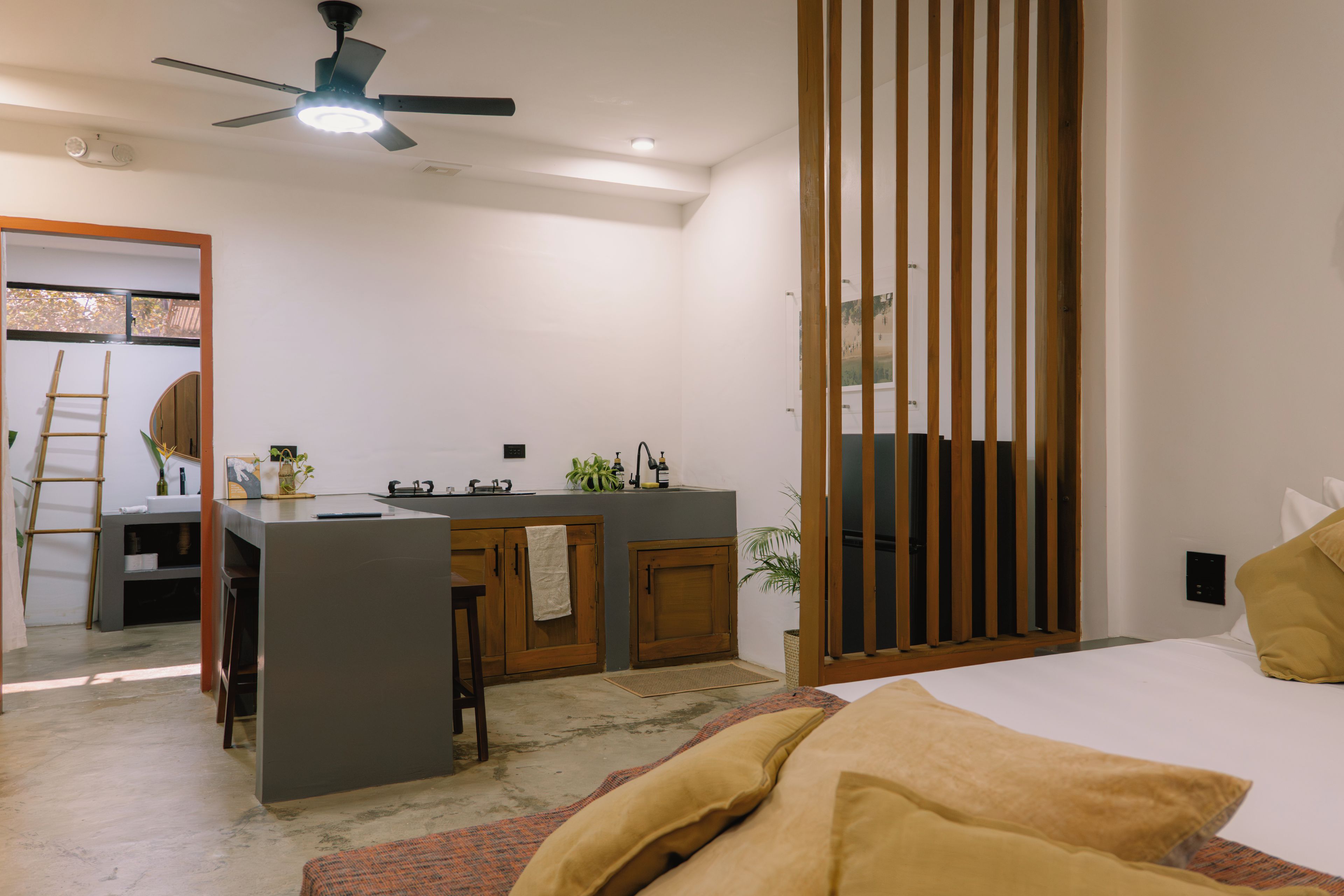 Une chambre moderne comprenant un lit, un bureau avec une chaise, un petit coin cuisine et une porte coulissante.