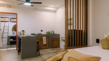 Une chambre moderne comprenant un lit, un bureau avec une chaise, un petit coin cuisine et une porte coulissante.