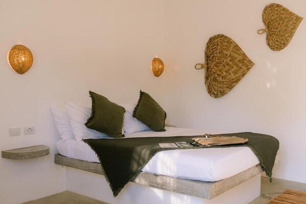 A bed with a wooden headboard, a bedside table, and a wall-mounted light fixture.
