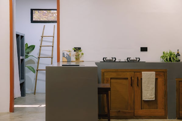A kitchen with a central island, wooden cabinets, a towel hanging on the door, and a ladder leaning against the wall.