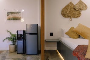 Une petite chambre comprenant un lit, un distributeur d’eau et un réfrigérateur.