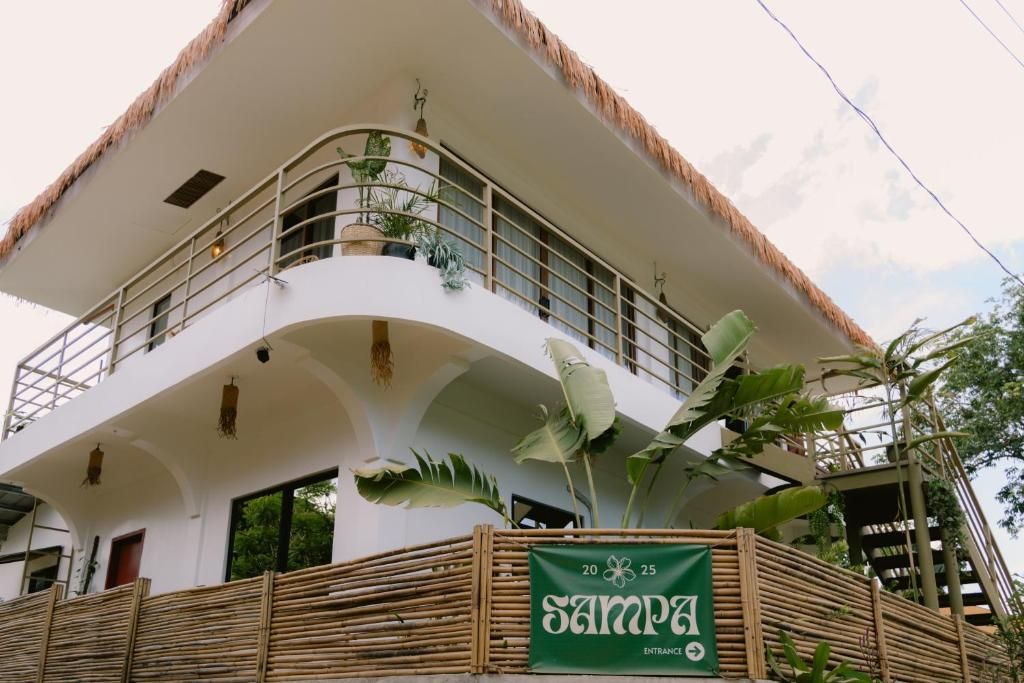 A multi-story building with a thatched roof, balconies with plants, and a sign indicating the entrance.