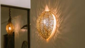 Une pièce avec un luminaire sphérique fixé au mur, une plante en pot et un lit.