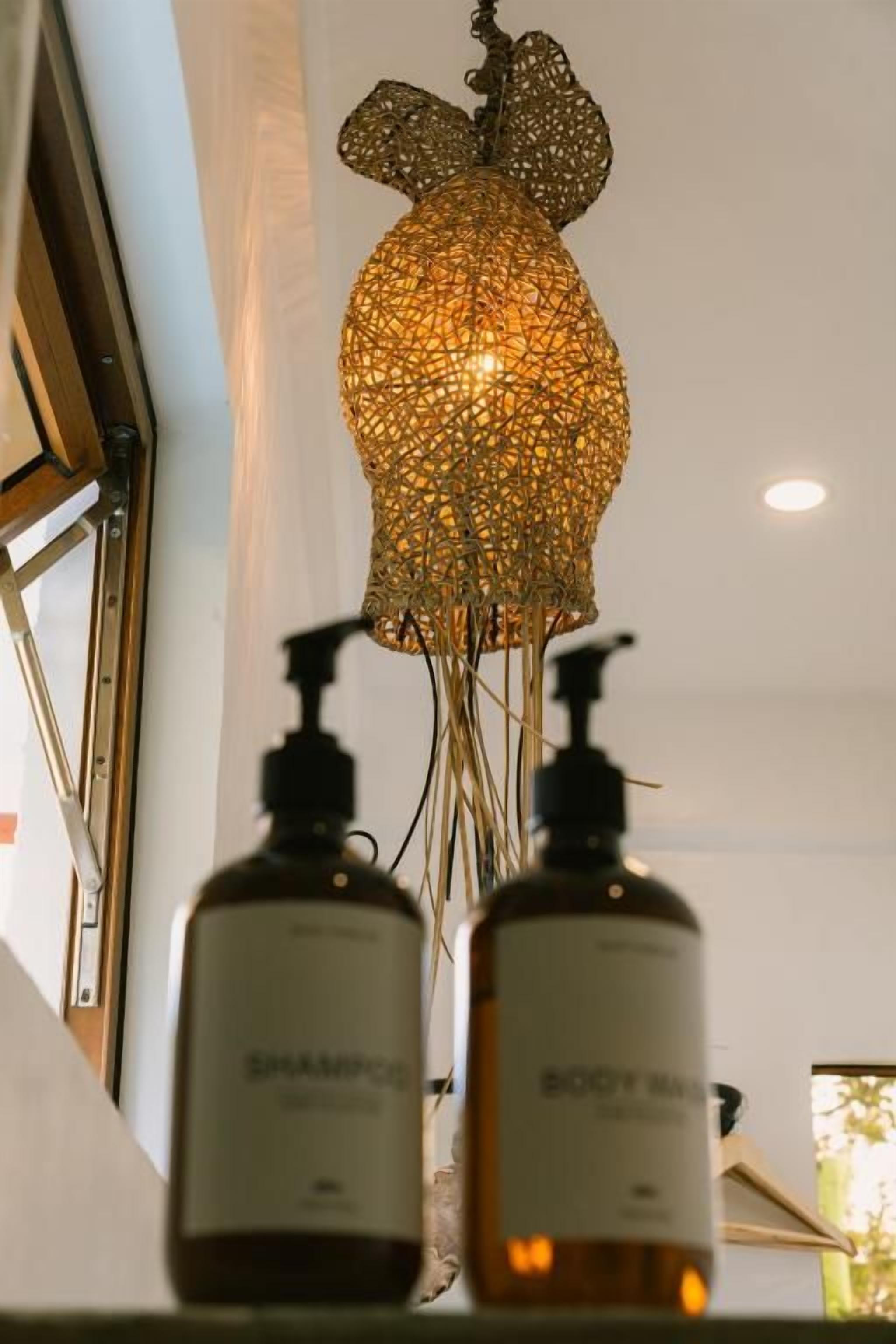 A bathroom with a unique pendant light fixture and two bottles of shampoo and body wash.
