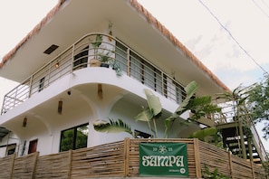 Un edificio de varios pisos con un balcón curvo, ventanas amplias y un letrero que indica la entrada.