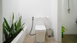 A small, white bathroom with a toilet, bidet, and a plant. - SAMPA El Nido (El Nido)