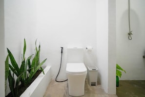 A small, white bathroom with a toilet, bidet, and a plant. - SAMPA El Nido (El Nido)