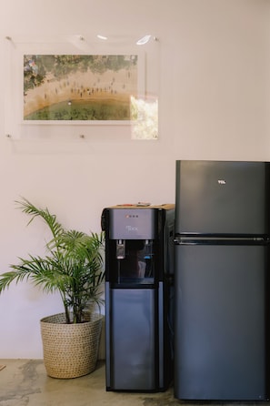 Un dispensador de agua y un refrigerador en una habitación con un cuadro en la pared.