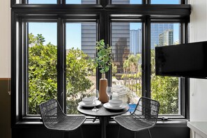 A dining area with a table, two chairs, a vase with a plant, and a TV on the wall. - Petco Park Nearby Walk to Gaslamp, Dine & Explore (San Diego)