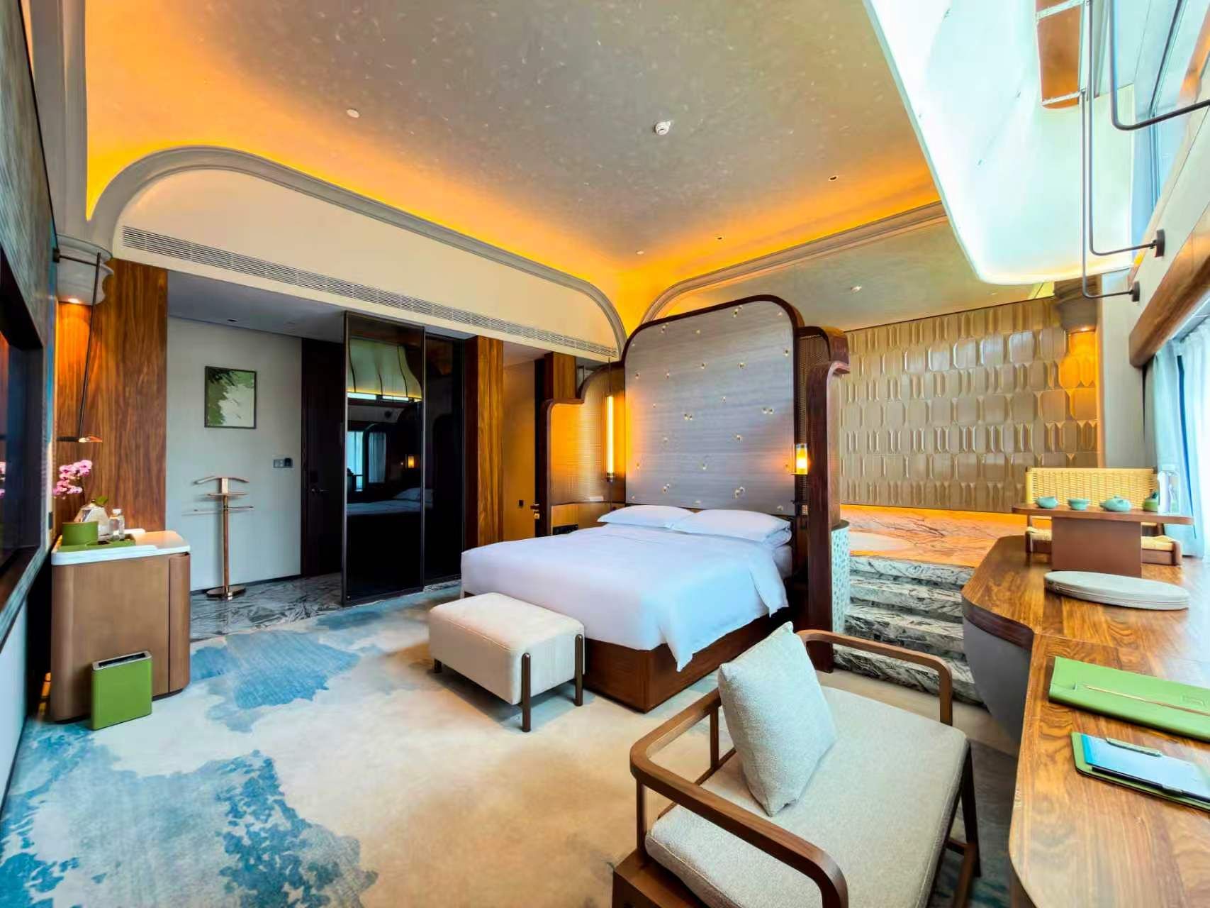 Habitación de hotel con una cama grande, zona de estar y vista al cielo.