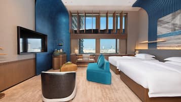 A hotel room with a large bed, a sofa, a TV, and a view of the city.