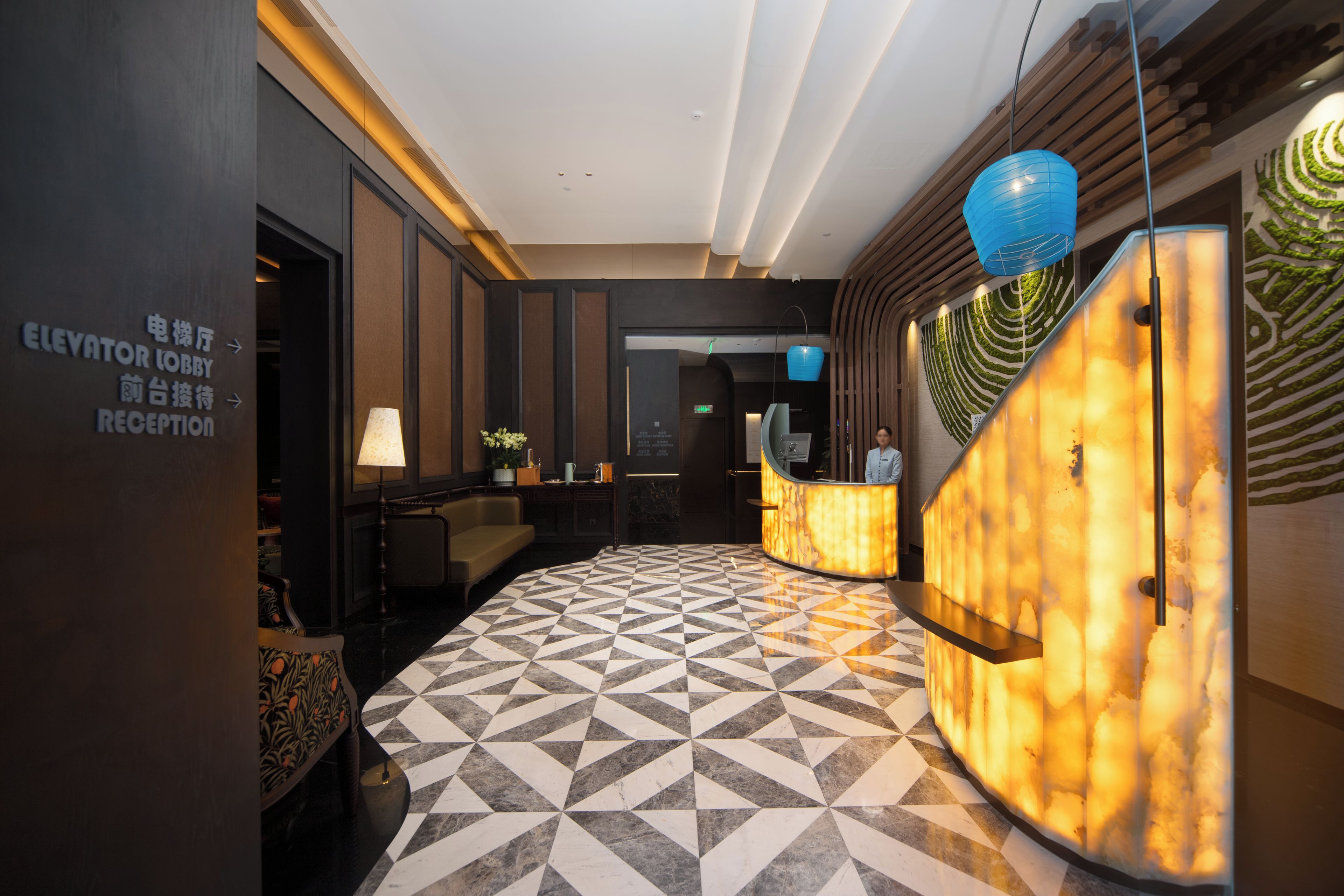 A hotel lobby with a reception desk, a check-in counter, and a geometric patterned floor.