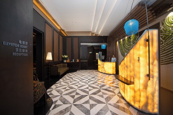 Un vestíbulo de hotel con una mesa de recepción, un mostrador de registro y un piso con diseño geométrico.