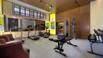 A gym with exercise equipment, seating areas, and a reception desk.