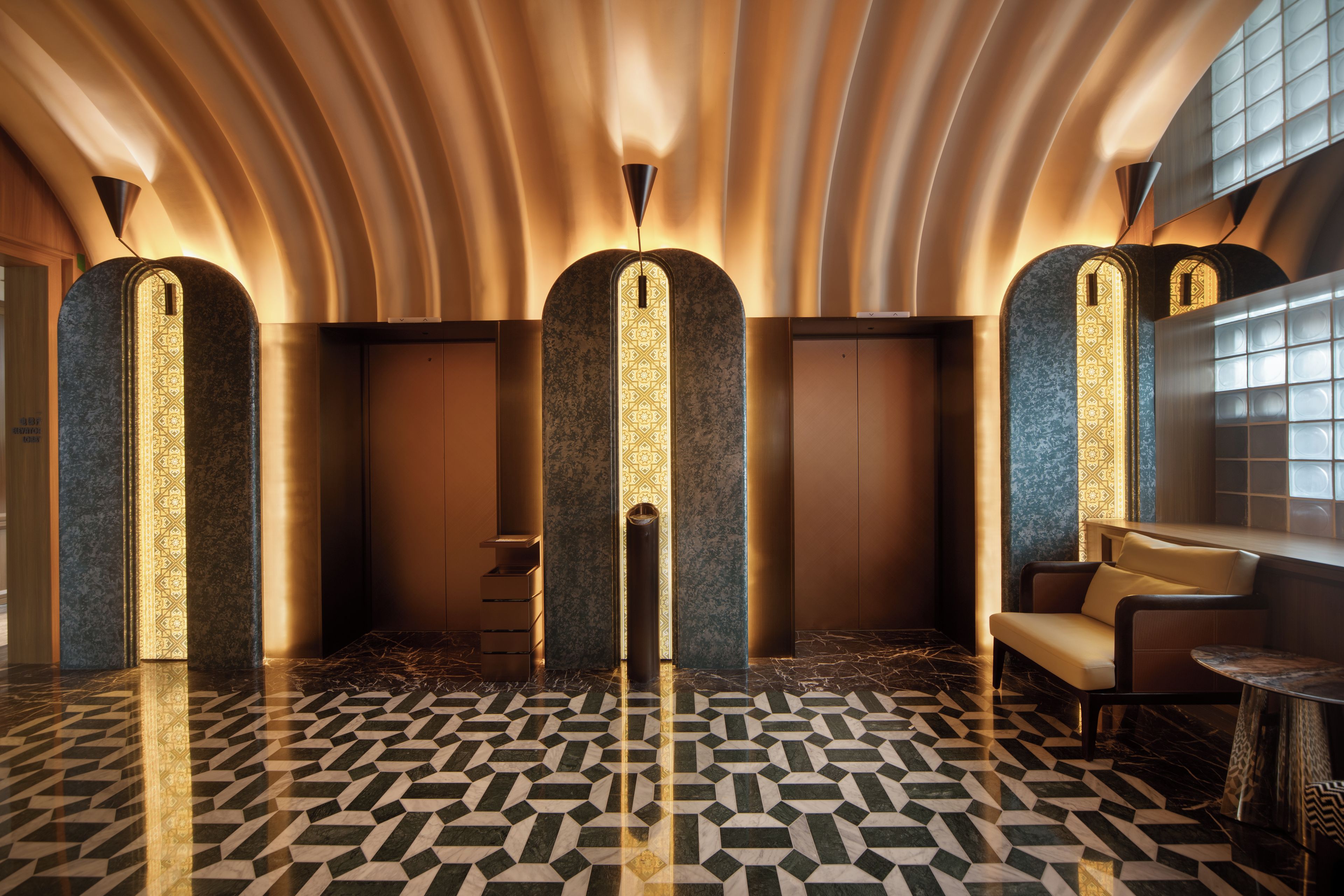 Un interno moderno con un pavimento a motivi geometrici, una zona salotto con un tavolo e una reception.