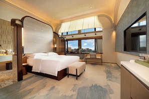 A modern hotel room with a large bed, a sitting area, and a view of the city. - Kunming Grand Metropark Hotel (Kunming)