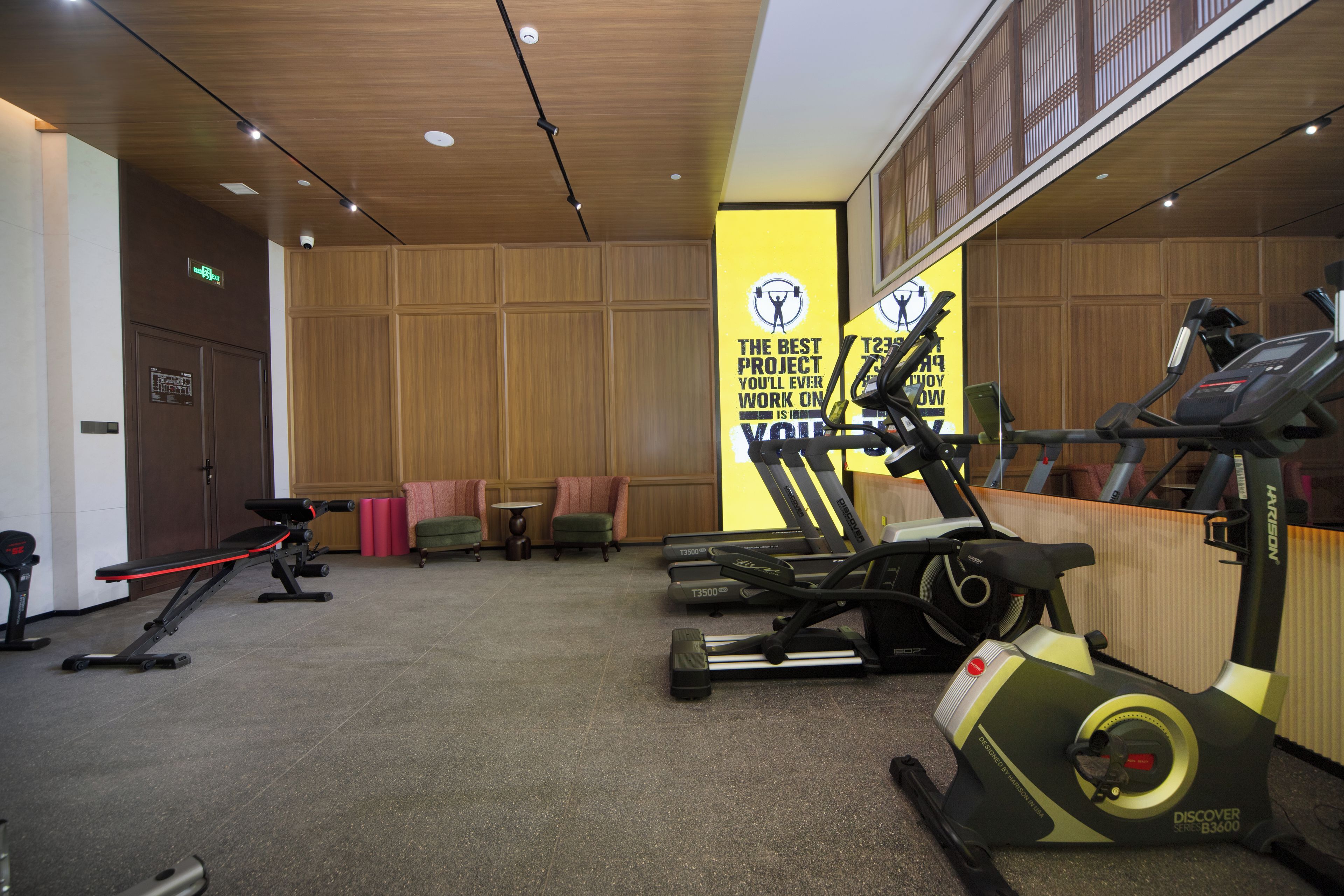 A gym with exercise equipment, a mirror, and a motivational poster.