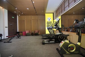 Un gimnasio con equipo de ejercicio, un espejo y un cartel motivacional.