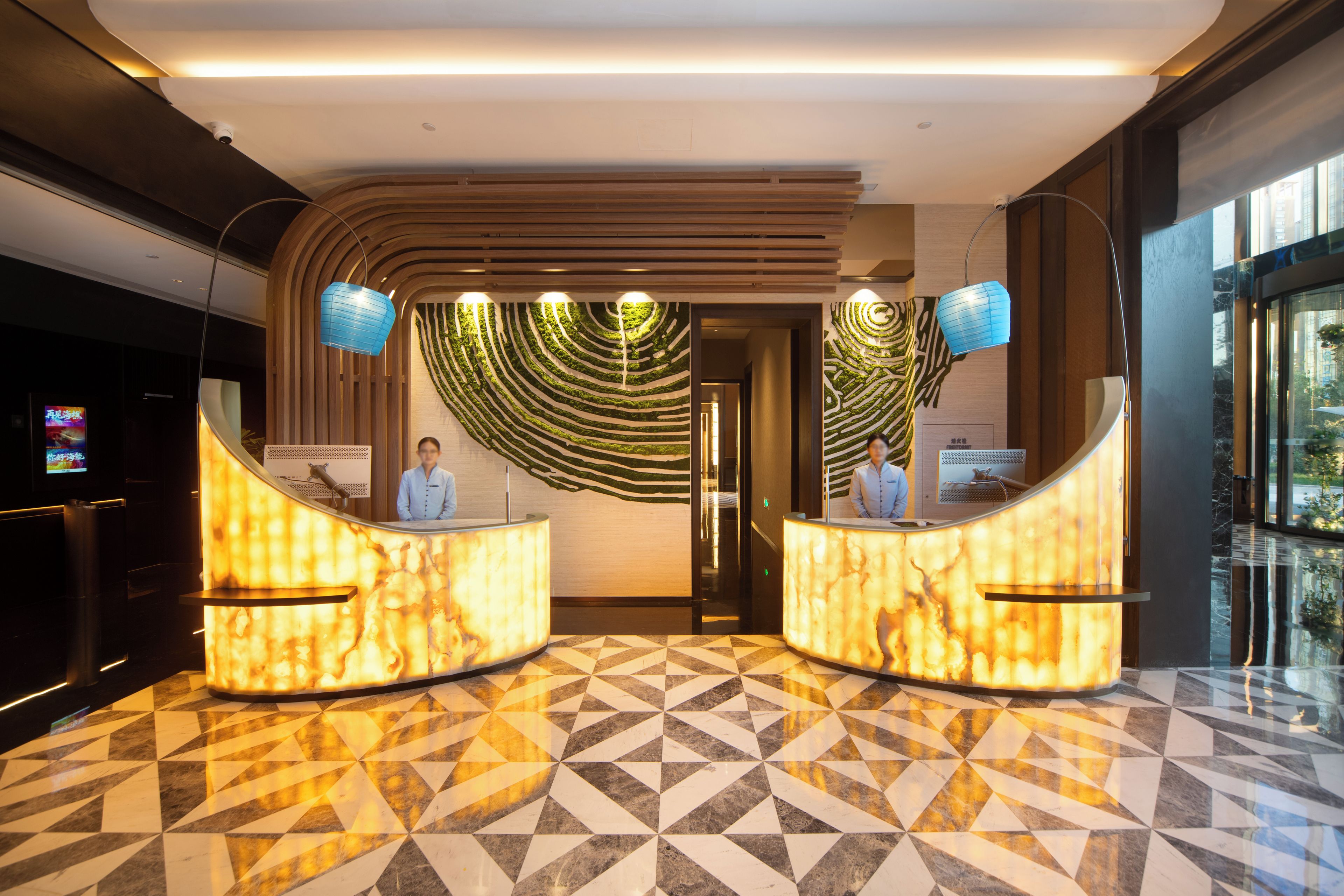 A hotel reception area with a modern design, featuring a marble floor and two reception desks.