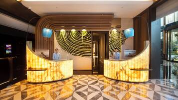 A hotel reception area with a modern design, featuring a marble floor and two reception desks.