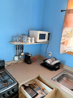 A compact kitchen with a microwave, a coffee maker, and a dish rack.