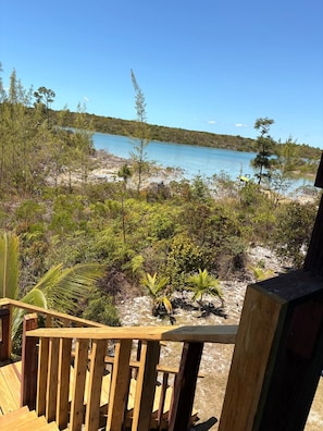 A wooden deck with a view of a beach and clear blue water.