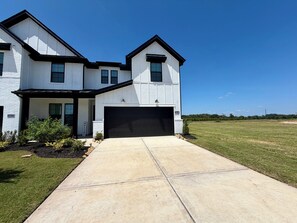 A modern two-story house with a black garage door, a well-maintained lawn, and a clear blue sky. - Modern 4 bedroom retreat spacious family friendly. (Katy)