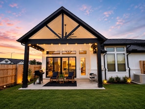 A covered patio with string lights, a grill, and outdoor seating. - Modern 4 bedroom retreat spacious family friendly. (Katy)