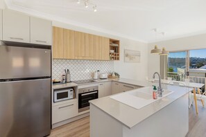 Eine moderne Küche mit Edelstahlgeräten, Holzschränken und einer großen Kochinsel mit Spüle.