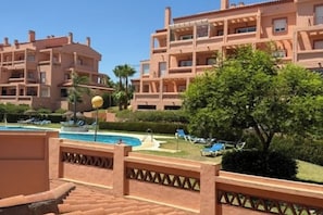 A hotel with multiple balconies, a swimming pool, and sun loungers. - Apartment Sleeps 8 with Pool and Parking (Malaga)