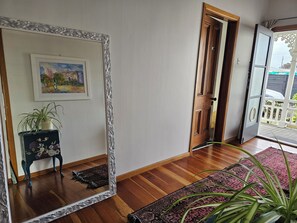 A room with a large mirror, a wooden door, a rug, and a potted plant. - Old-World Villa Charm in the Heart of Featherston • 2 Beds • Walk to Town (Featherston)