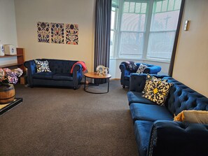 A living room with two sofas, a coffee table, and a decorative vase with flowers. - Old-World Villa Charm in the Heart of Featherston • 2 Beds • Walk to Town (Featherston)